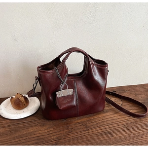 Dettaglio macro della borsa tote in ecopelle bordeaux con catena d'argento e charm