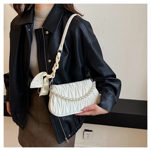 Detail of white pleated shoulder bag featuring elegant pearl chain and silk bow strap