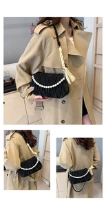 Detail of black pleated shoulder bag with elegant pearl chain and yellow ribbon strap
