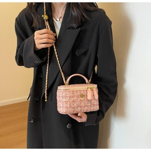 Detailed view of pink tweed box bag with gold camellia charm and metal chain strap
