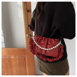 Detail of red pleated handbag with white pearl chain and soft shoulder strap