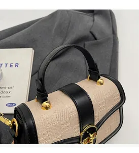 Detail of vintage beige textured leather mini bag with gold rotary lock on grey fabric