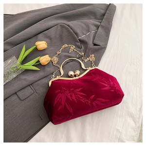 Macro detail of red velvet evening bag featuring bamboo patterns and pearl clasp closure