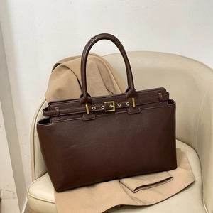 Retro large capacity dark brown leather tote bag with gold buckle on a beige seat