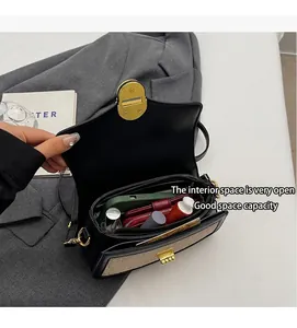 Detail view of the interior compartment of a black crossbody bag with gold hardware