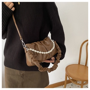 Brown ruched handbag with pearl chain and adjustable strap shown on a model