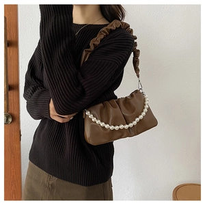 Detail of brown pleated shoulder bag with elegant pearl chain and soft PU texture