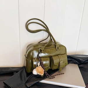 Vintage olive green Boston handbag with pockets and baseball charm on a leather jacket