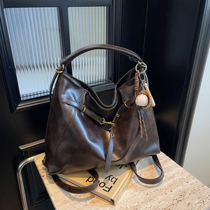 Vintage dunkelbraune Hobo-Tasche aus Kunstleder mit Baseball-Anhänger auf Display