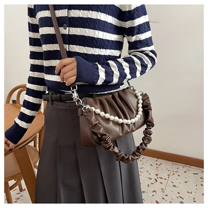 Close-up of brown pleated cloud bag with elegant pearl chain and leather shoulder strap