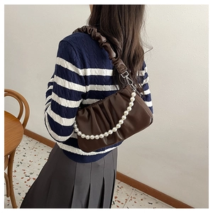 Detail of dark brown pleated hobo bag with vintage texture and elegant pearl chain strap
