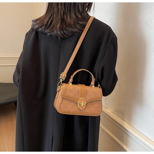 Brown checkerboard textured square crossbody bag worn with a black blazer for chic style