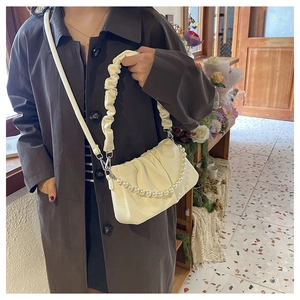 Detail of creamy white pleated cloud bag featuring elegant pearl chain and soft texture
