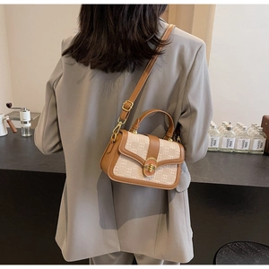 Brown leather trimmed crossbody square bag with metal twist lock in a cafe setting