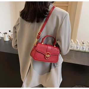 Detail of burgundy checkered crossbody bag with gold buckle on a model in a cafe