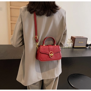 Red retro embossed crossbody bag with gold metal lock worn with a grey blazer