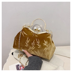 Close-up of velvet handbag with bamboo leaf patterns and pearl clasp closure
