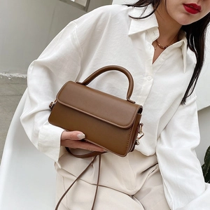 Sac bandoulière en cuir mat marron avec poignée et finitions dorées en vue diagonale