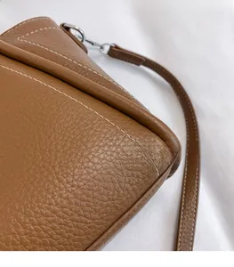Detail of brown pebbled PU leather bag featuring white contrast stitching and silver hardware