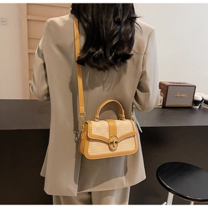 Detail of elegant beige jacquard small square bag with brown leather trim and metal lock