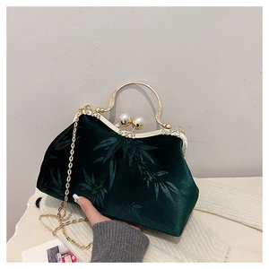 Detail of dark green velvet handbag with bamboo patterns and golden ring handle