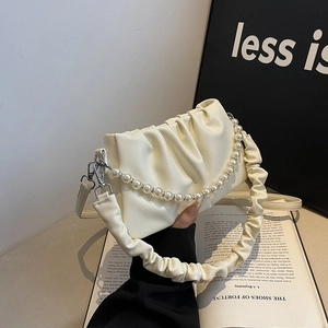 Chic pleated cream cloud handbag with pearl chain decoration on a minimalist background