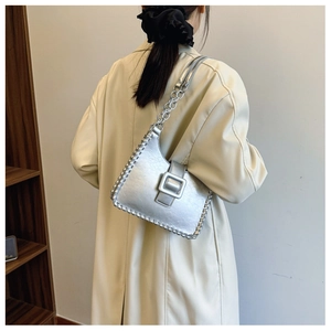 Close-up of silver shoulder bag with woven edges and metallic chain strap on model