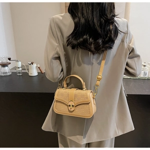 Detail of khaki textured crossbody bag with gold oval lock and slim shoulder strap