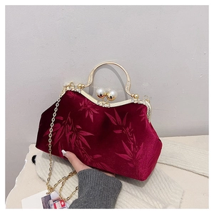 Close-up of red velvet evening bag with bamboo leaf print and pearl clasp detail