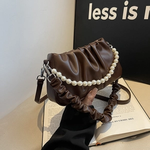 Dark brown pleated cloud bag with pearl handle and wide shoulder strap in studio setting