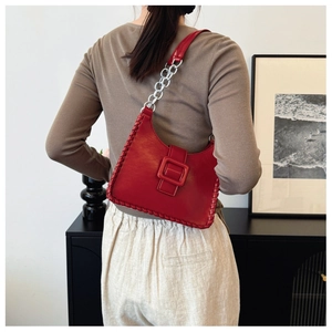 Detail of red shoulder bag with hand-woven edges and stylish silver chain strap