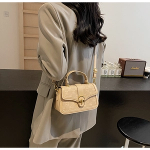 Detail of beige textured crossbody square bag with vintage floral embossing and gold lock
