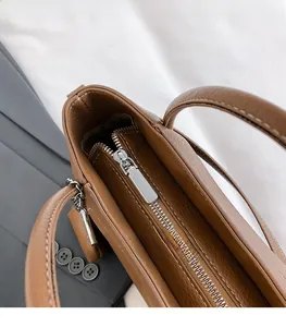 Macro shot of silver metal zipper detail on brown pebbled leather handbag with smooth glide