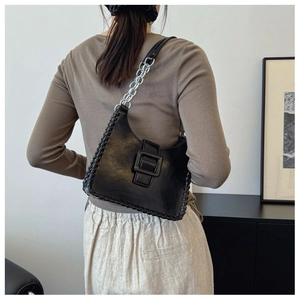 Detail of black matte leather bag with woven edges and silver chain strap