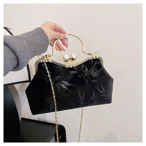 Detail of vintage black velvet clutch featuring pearl clasp and gold bamboo patterns