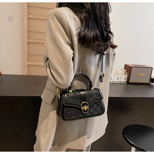 Detail view of the black checkered texture and gold rotary lock on this stylish bag