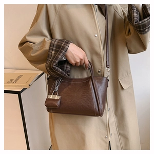 Detail of dark brown pebble leather tote with contrast stitching and mini bag charm