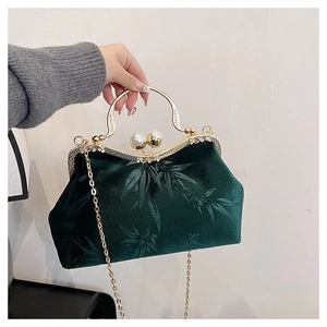 Detailed view of dark green velvet bag with bamboo pattern and pearl clasp closure