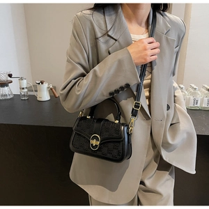 Detail of vintage black crossbody bag with jacquard pattern and gold buckle