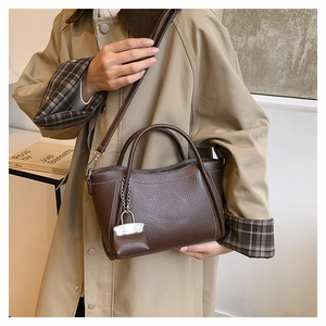 Detail of dark brown pebble leather handbag with twin handles and a matching mini charm