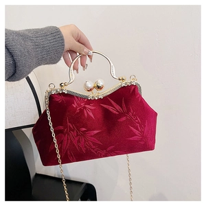 Detail of dark red velvet handbag with bamboo pattern, gold handle and pearl clasp
