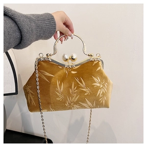 Macro shot of mustard yellow velvet clutch with bamboo patterns and pearl clasp closure