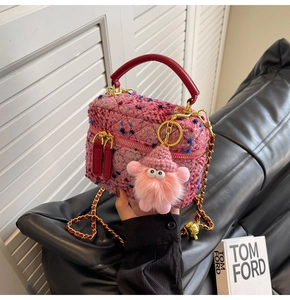 Detailed close-up of pink tweed mini bag with plush monster charm and golden chain