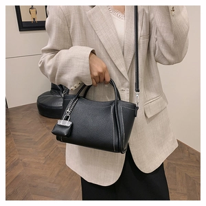 Detail of black lychee grain PU leather handbag with white contrast stitching accents