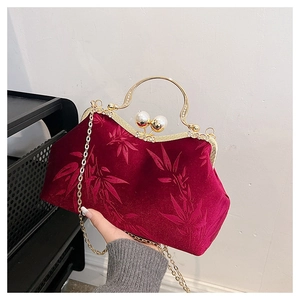 Detail of red velvet handbag with bamboo leaf embroidery and elegant pearl clasp