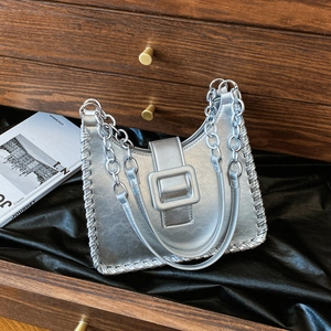Silver crescent hobo bag with metal buckle and chain strap on dark silk background