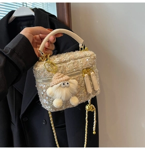 Close-up of tweed handbag with sequins, golden chain strap and a plush charm