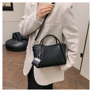 Close-up of black lychee grain leather tote with white contrast stitching and coin purse