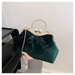 Detail of dark green velvet handbag with bamboo patterns and pearl metal clasp