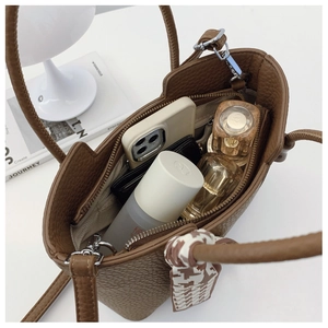 Detailed interior of brown pebble leather tote bag showing capacity for phone and cosmetics